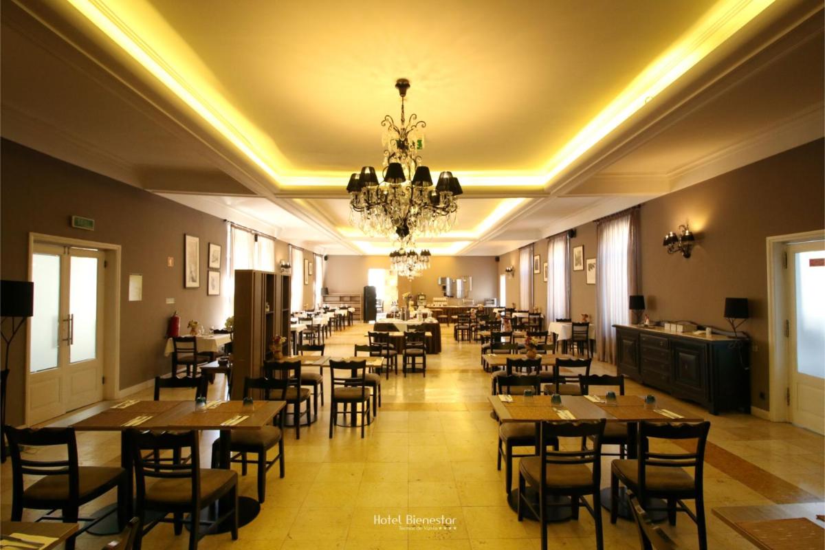 um restaurante com mesas e cadeiras e um lustre em Hotel Bienestar Termas De Vizela em Vizela