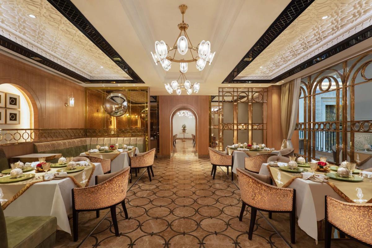a restaurant with tables and chairs and a chandelier at ITC Narmada, a Luxury Collection Hotel, Ahmedabad in Ahmedabad