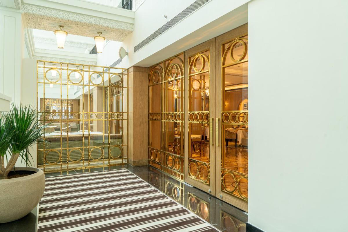 a lobby with gold doors and a room with a table at ITC Narmada, a Luxury Collection Hotel, Ahmedabad in Ahmedabad