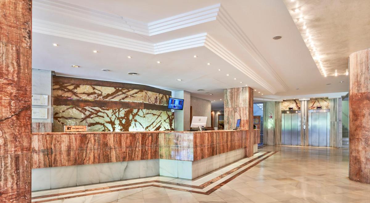 Un vestíbulo de un hotel con un mostrador de recepción. en Hotel Serrano Palace, en Cala Ratjada
