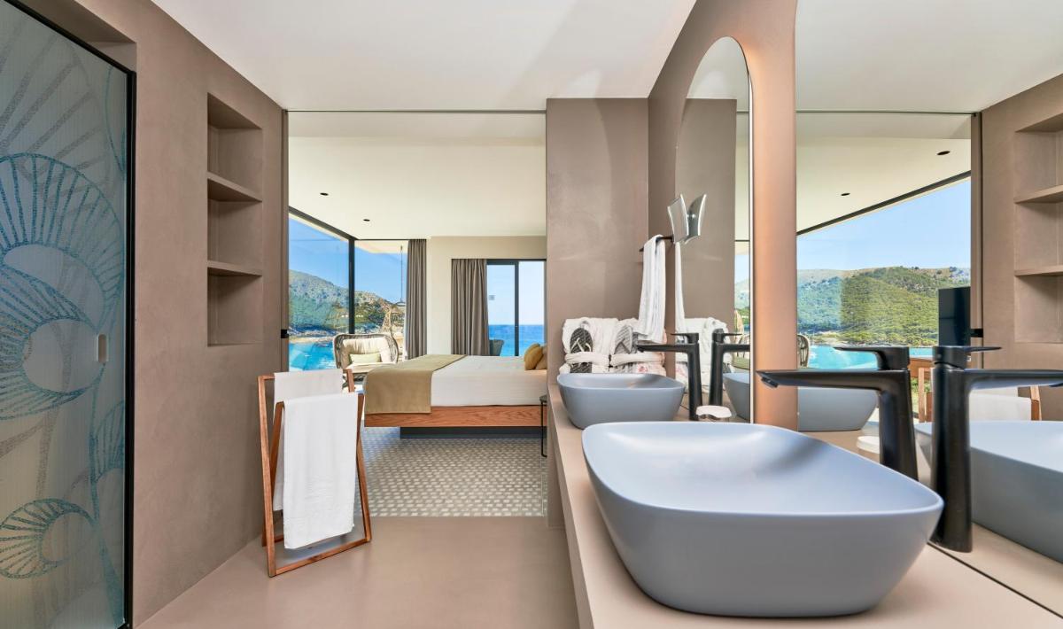 Un baño con dos lavabos y bañera y un baño con vistas. en Hotel & Spa S'Entrador Playa, en Cala Ratjada