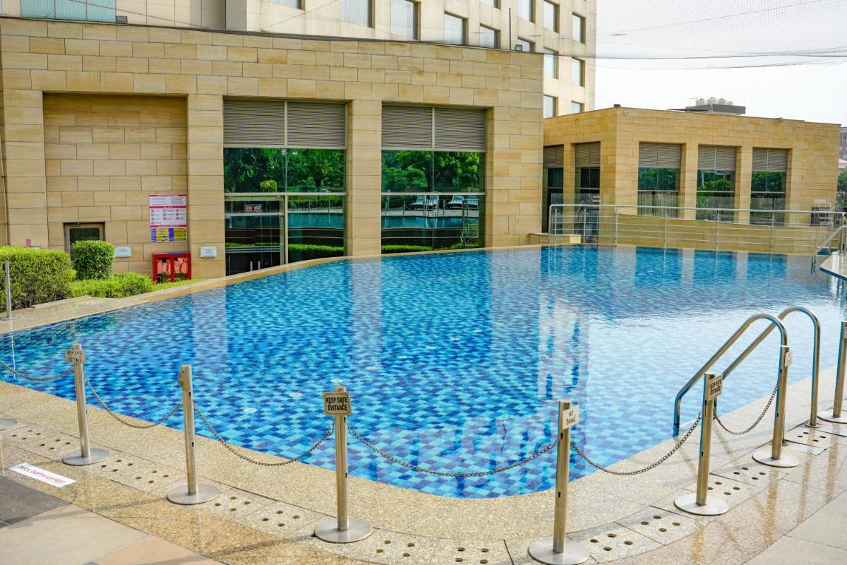 a large blue swimming pool in front of a building at Courtyard by Marriott Gurugram Downtown in Gurgaon