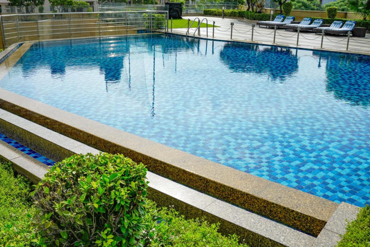 a large swimming pool with chairs in a building at Courtyard by Marriott Gurugram Downtown in Gurgaon