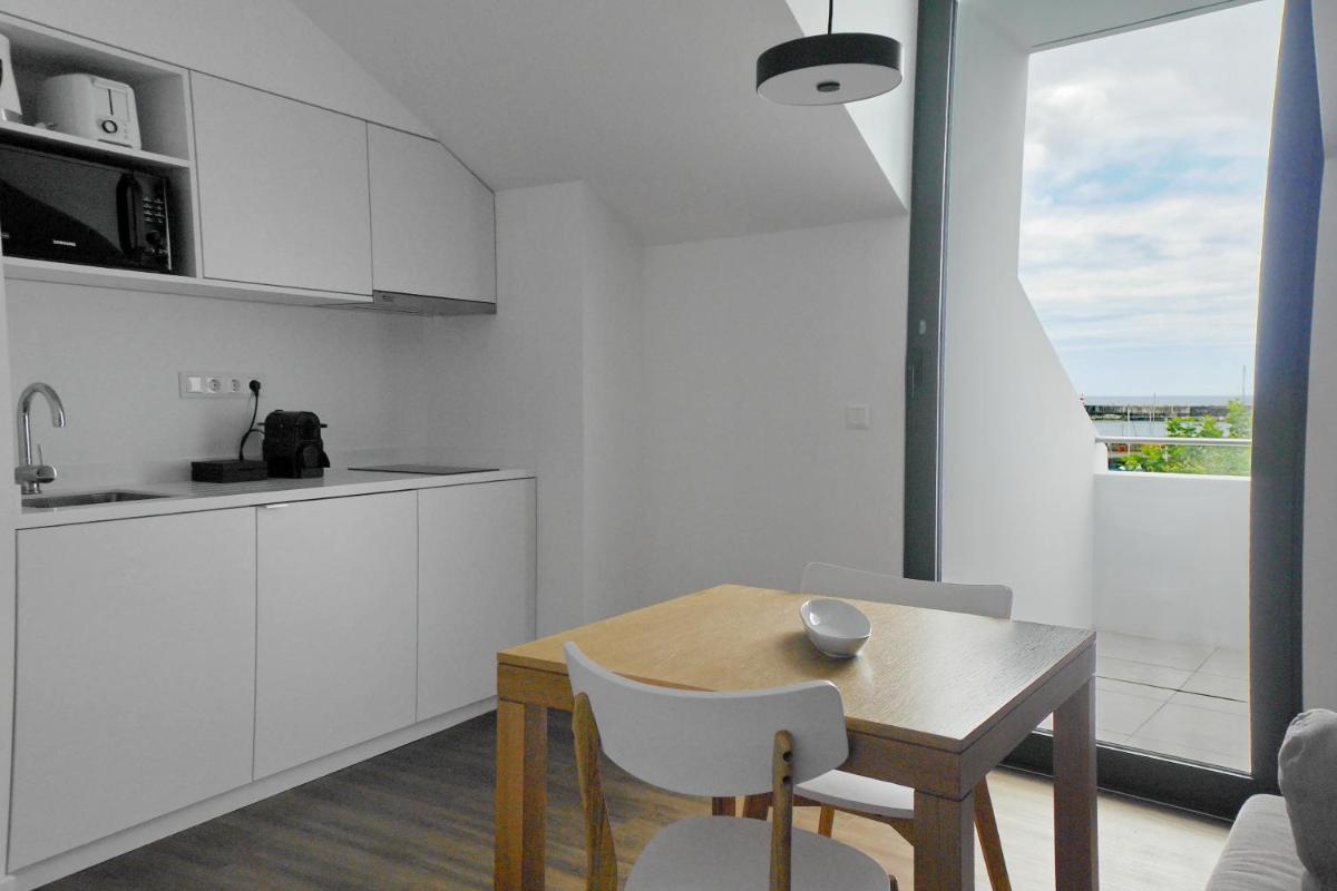 uma cozinha com uma mesa de madeira e armários brancos em Pêro Teive Bay Apartments Hotel em Ponta Delgada