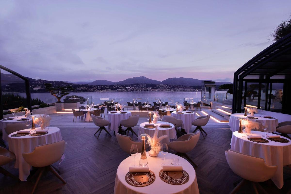 - un restaurant avec des tables et des chaises blanches offrant une vue dans l'établissement Hôtel Marinca & Spa, à Olmeto