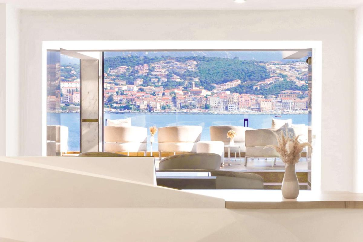 une pièce avec une table et des chaises et une grande fenêtre dans l'établissement Hôtel Marinca & Spa, à Olmeto une pièce avec une table et des chaises et une grande fenêtre dans l'établissement Hôtel Marinca & Spa, à Olmeto