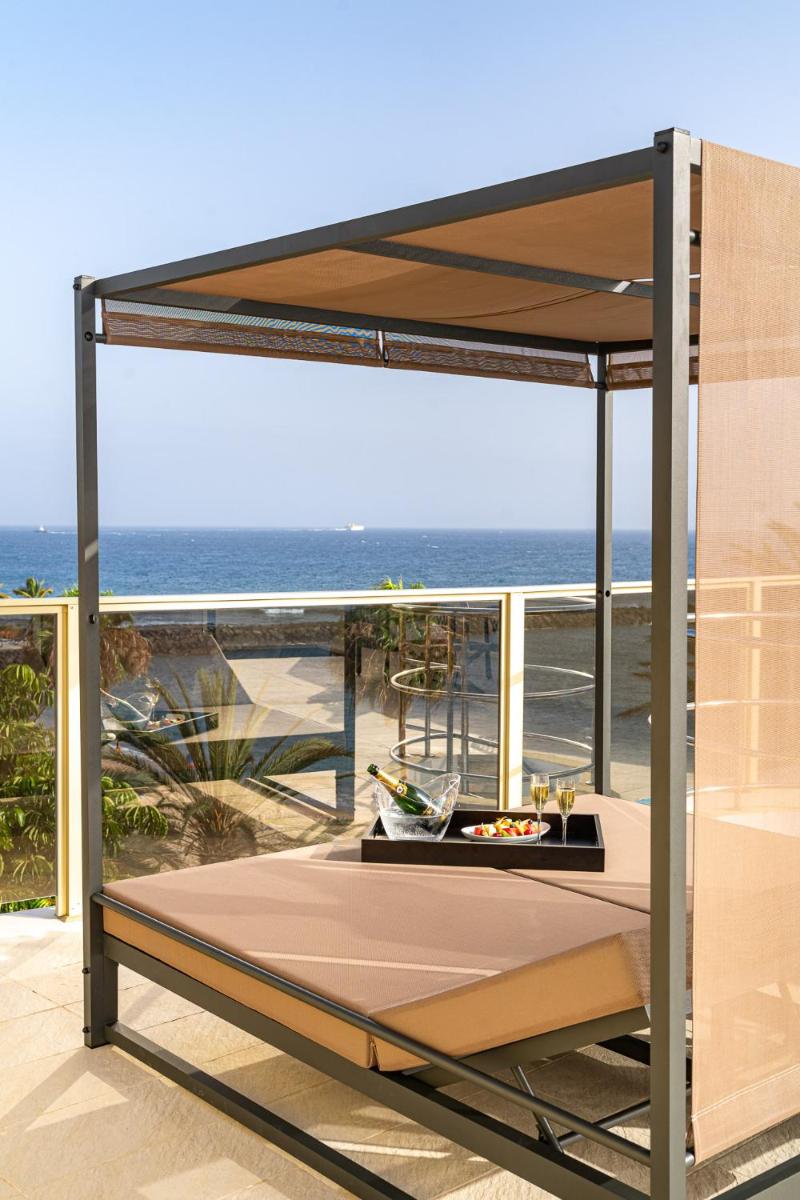 una cama con dosel en un balcón con vistas al océano en Sir Anthony, en Playa de las Américas