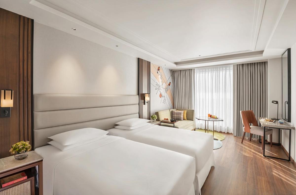 a hotel room with two white beds and a desk at Hyatt Centric Rajpur Road Dehradun in Dehradun
