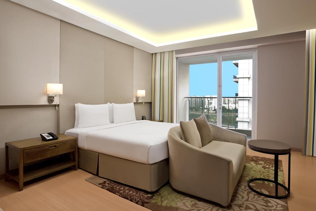 a hotel room with a bed and a chair and a window at DoubleTree Suites by Hilton Bengaluru Outer Ring Road in Bengaluru