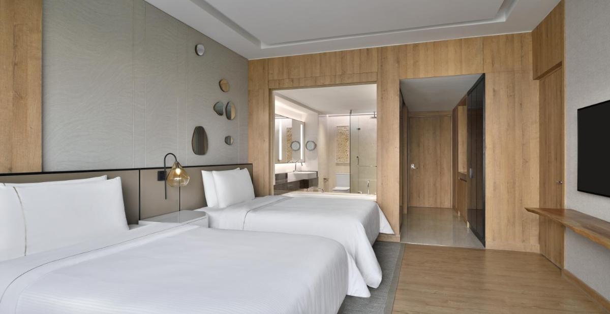 two beds in a hotel room with a television at The Westin Mumbai Powai Lake in Mumbai