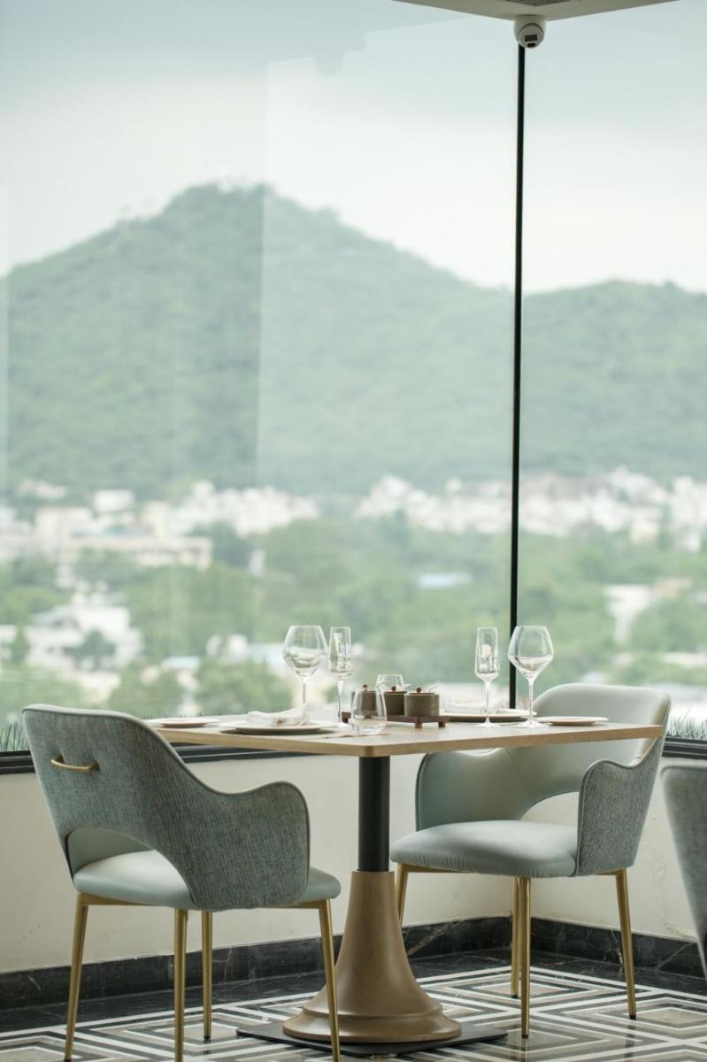 a table and chairs in a room with a window at Parallel Hotel Udaipur, a member of Radisson Individuals in Udaipur