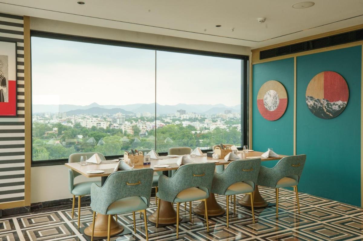 a dining room with tables and chairs and large windows at Parallel Hotel Udaipur, a member of Radisson Individuals in Udaipur