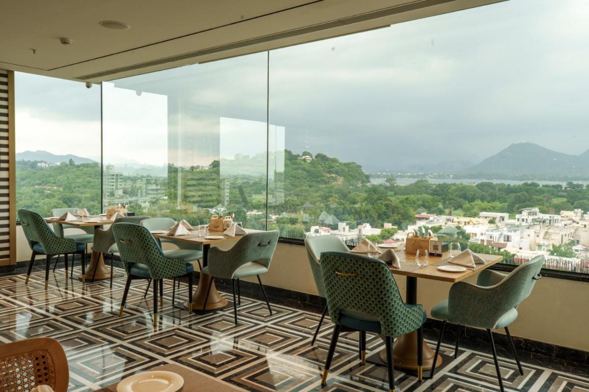 a restaurant with tables and chairs and large windows at Parallel Hotel Udaipur, a member of Radisson Individuals in Udaipur