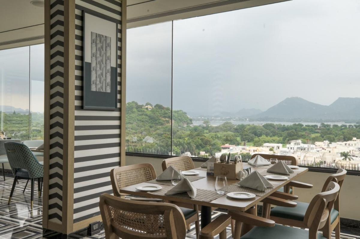 a dining room with a table and chairs and large windows at Parallel Hotel Udaipur, a member of Radisson Individuals in Udaipur