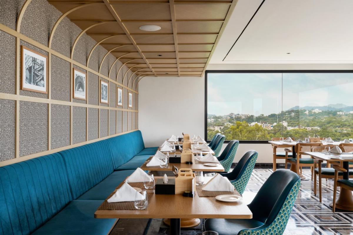 a restaurant with wooden tables and chairs and a large window at Parallel Hotel Udaipur, a member of Radisson Individuals in Udaipur