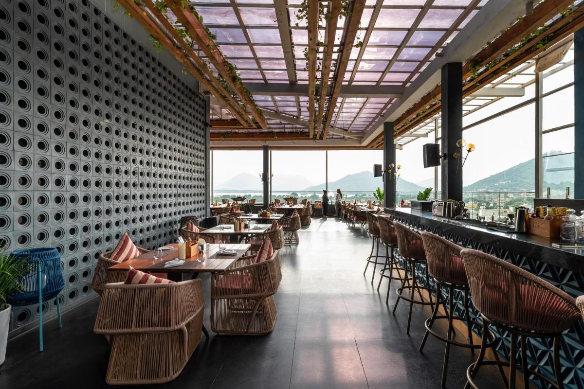 a restaurant with tables and chairs with mountains in the background at Parallel Hotel Udaipur, a member of Radisson Individuals in Udaipur