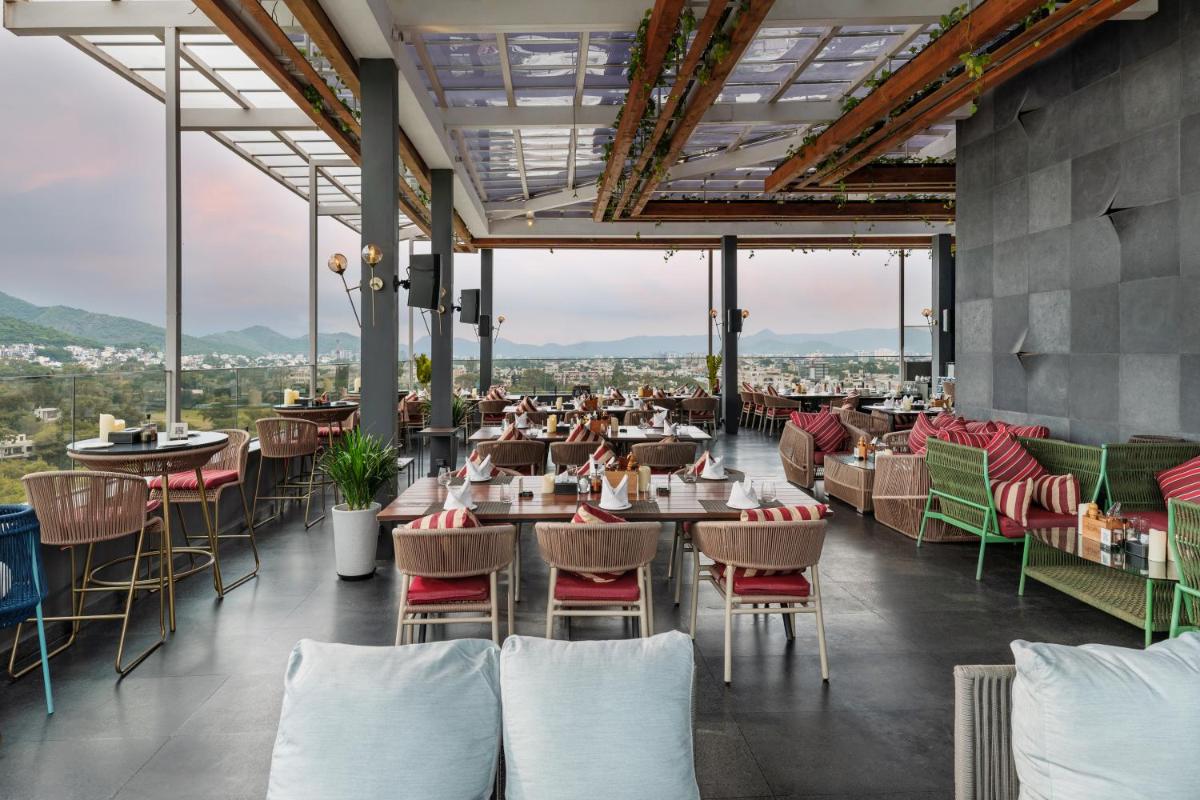 a restaurant with tables and chairs with a view at Parallel Hotel Udaipur, a member of Radisson Individuals in Udaipur