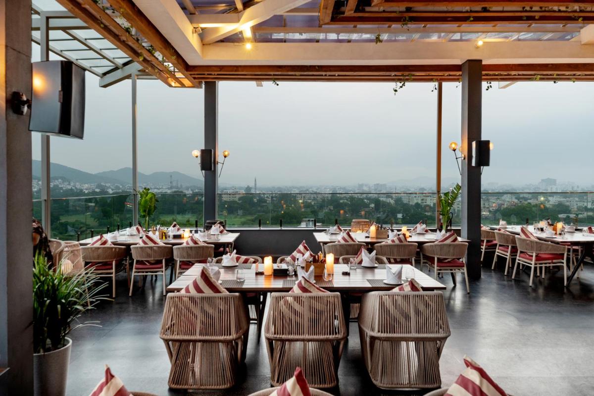 a restaurant with tables and chairs and large windows at Parallel Hotel Udaipur, a member of Radisson Individuals in Udaipur