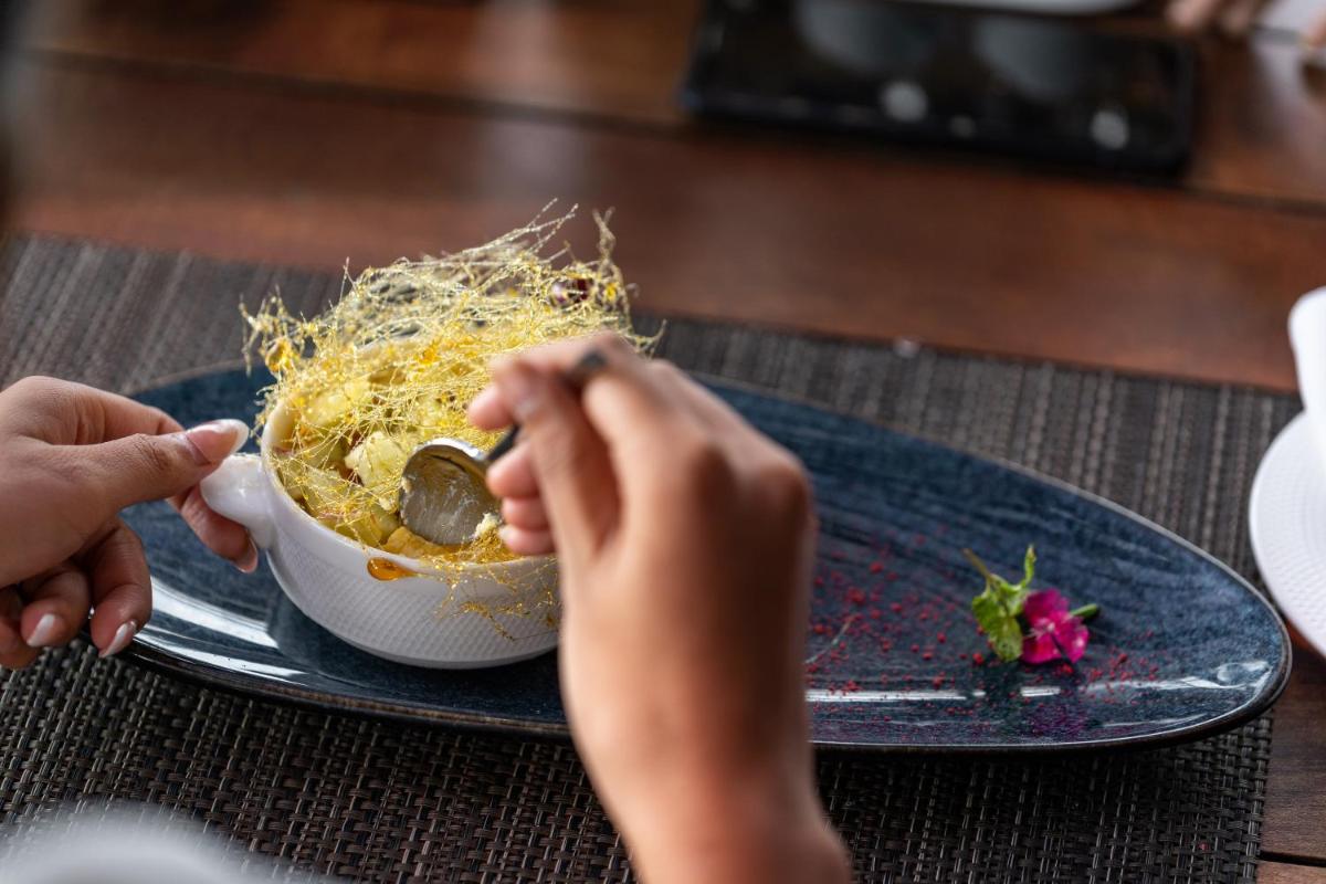 a person eating a bowl of food on a table at Parallel Hotel Udaipur, a member of Radisson Individuals in Udaipur