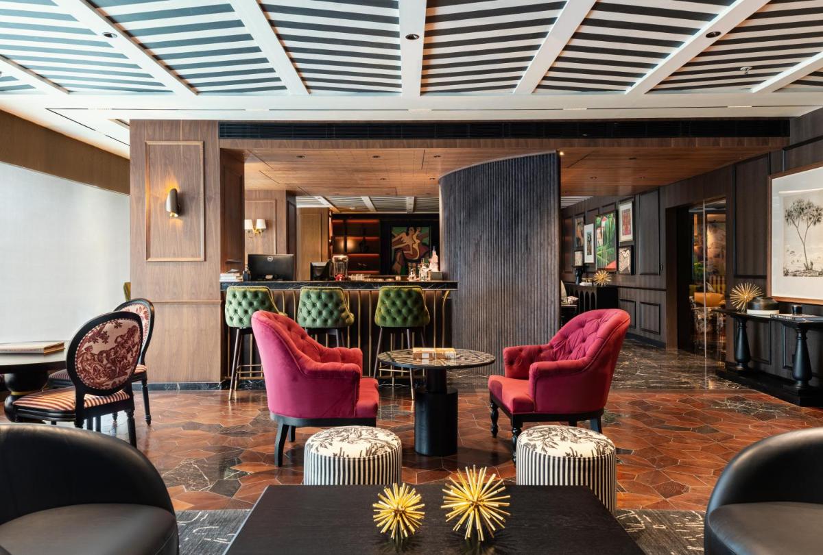 a lobby with red chairs and a bar at Parallel Hotel Udaipur, a member of Radisson Individuals in Udaipur