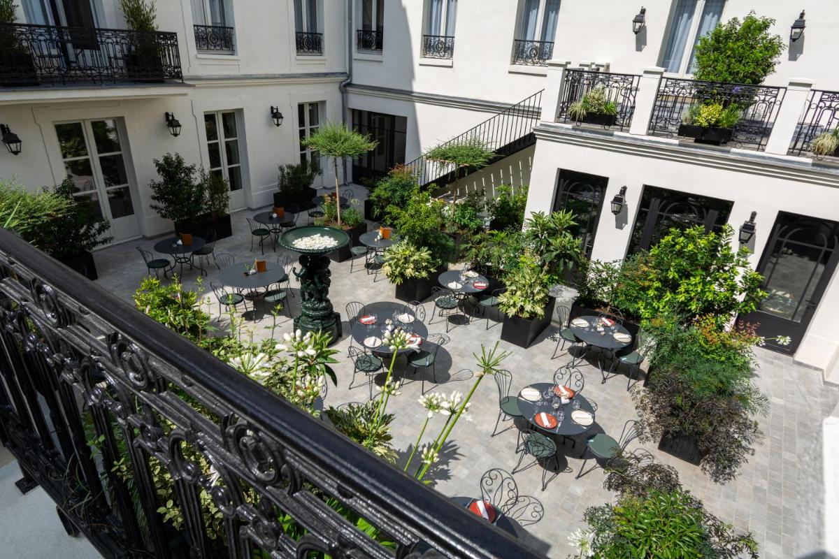 une terrasse extérieure avec tables et chaises devant un bâtiment dans l'établissement Hôtel & SPA Napoléon, à Fontainebleau