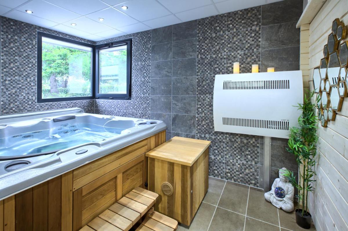 une salle de bain avec une grande baignoire et une fenêtre dans l'établissement Logis Hotel Restaurant & SPA Au Comte d'Ornon, à Gradignan 28 autres photos