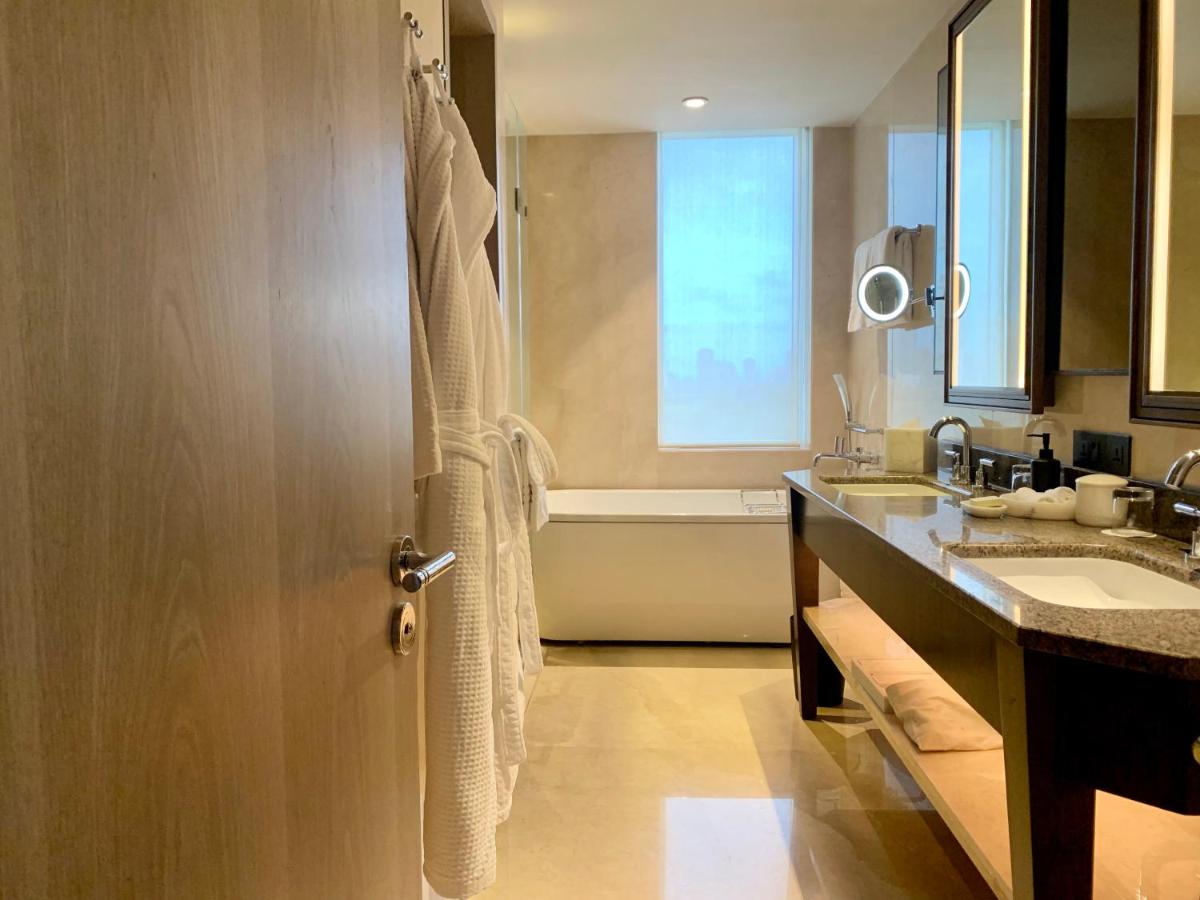 a bathroom with a door with a sink and a tub at Four Seasons Hotel Mumbai in Mumbai