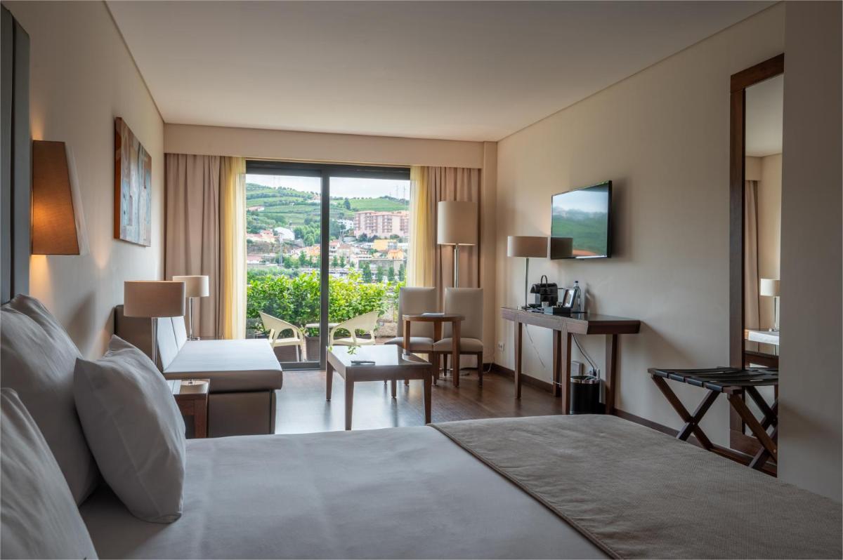 um quarto de hotel com uma cama e uma sala de estar em Vila Gale Collection Douro em Lamego