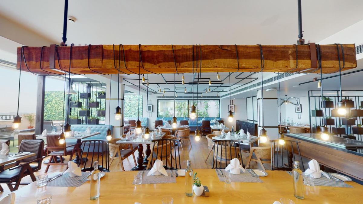 a dining room with tables and chairs and windows at Radisson Hotel Shimla in Shimla