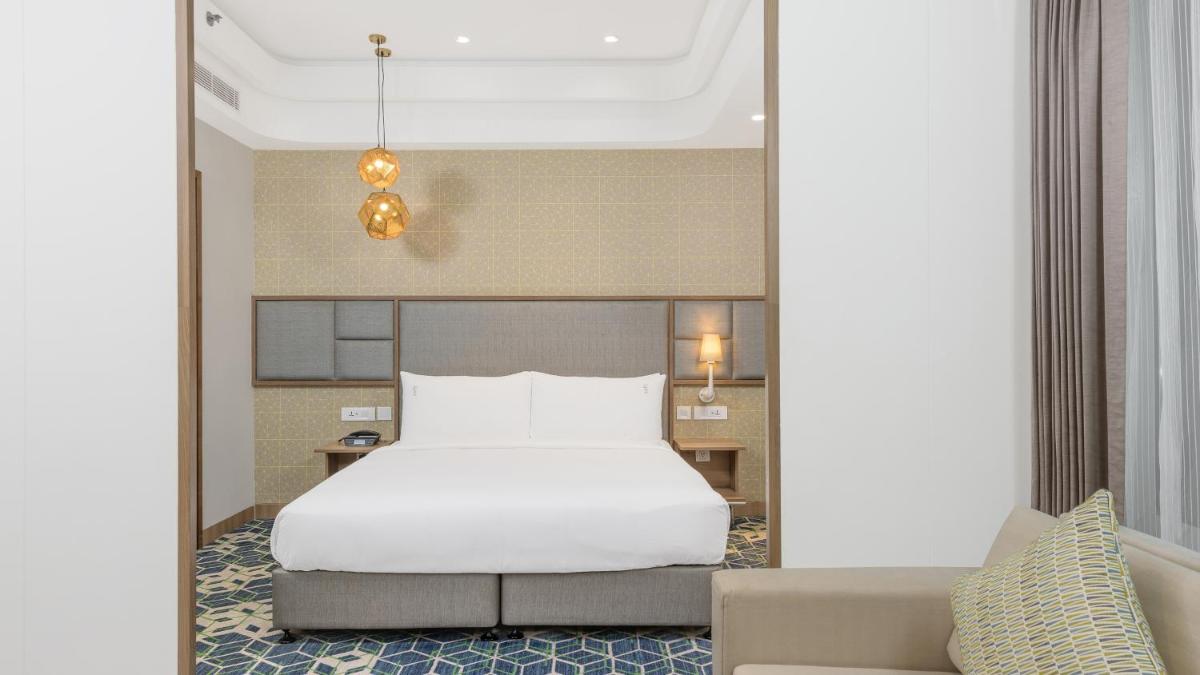 a bedroom with a white bed and a couch at Holiday Inn Gurugram Sector 90 by IHG in Gurgaon