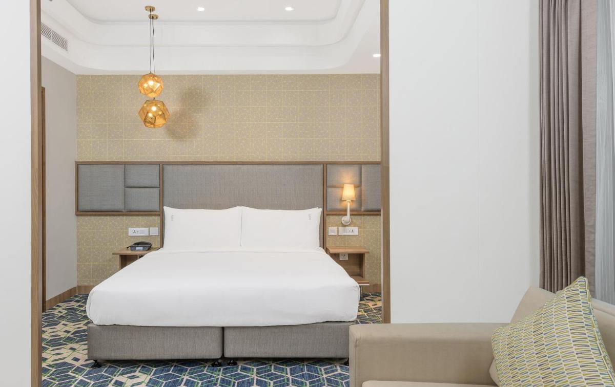 a bedroom with a white bed and a couch at Holiday Inn Gurugram Sector 90 by IHG in Gurgaon