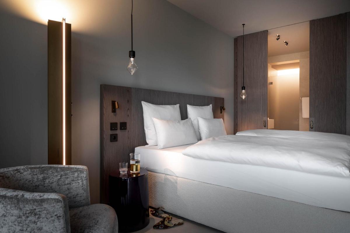 ein Schlafzimmer mit einem großen weißen Bett und einem Stuhl in der Unterkunft RIVA - Das Hotel am Bodensee in Konstanz