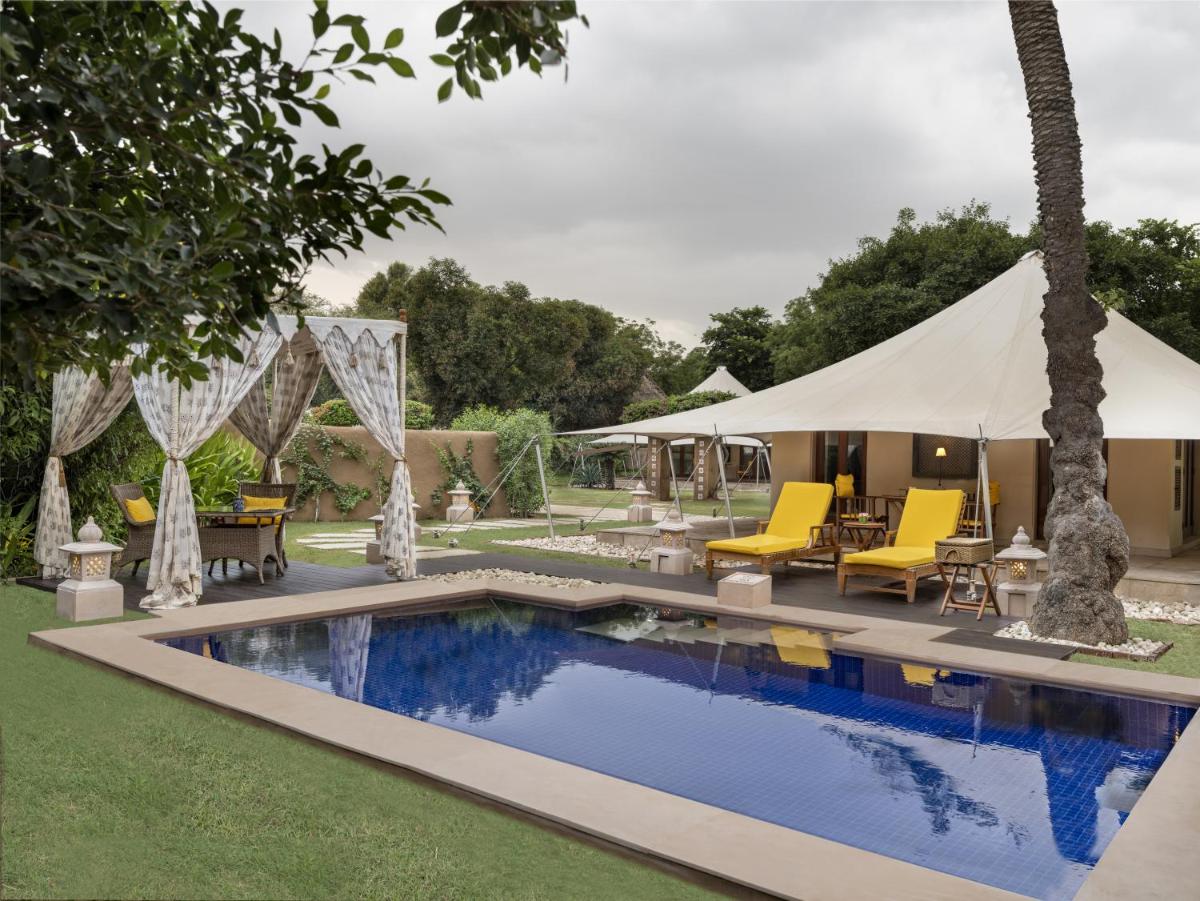 a swimming pool in a yard with chairs and a tent at The Oberoi Rajvilas Jaipur in Jaipur