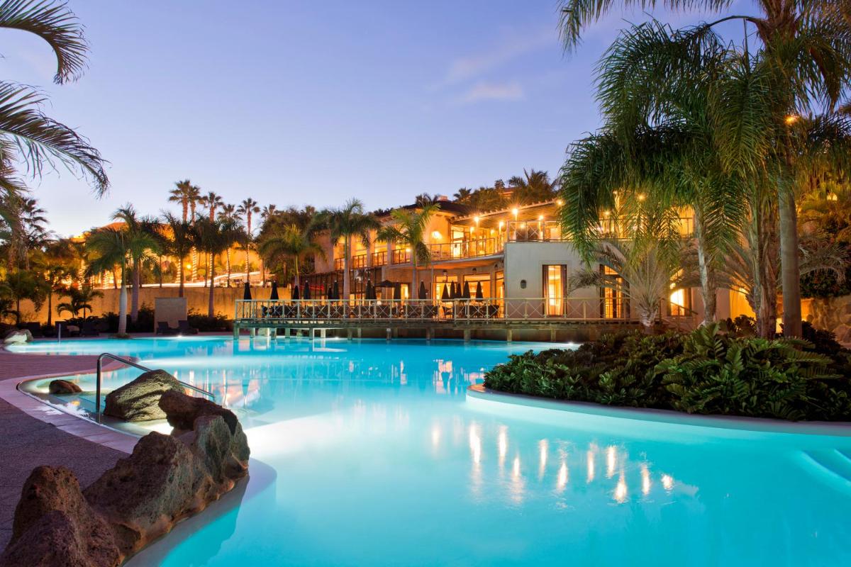 Una gran piscina con palmeras en un complejo turístico. en The Villas at Bahia del Duque, en Adeje