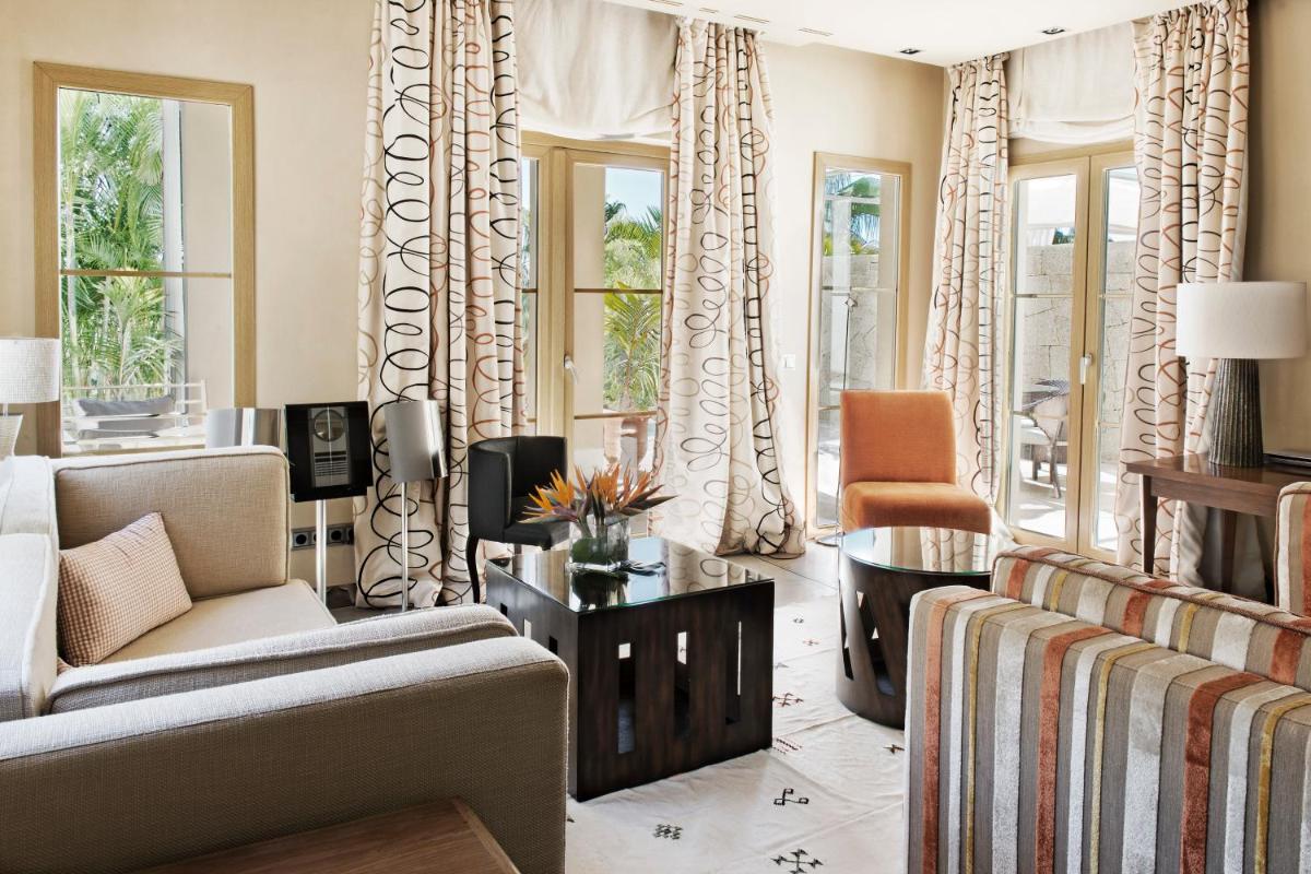 una sala de estar con un sofá y una silla en The Villas at Bahia del Duque, en Adeje