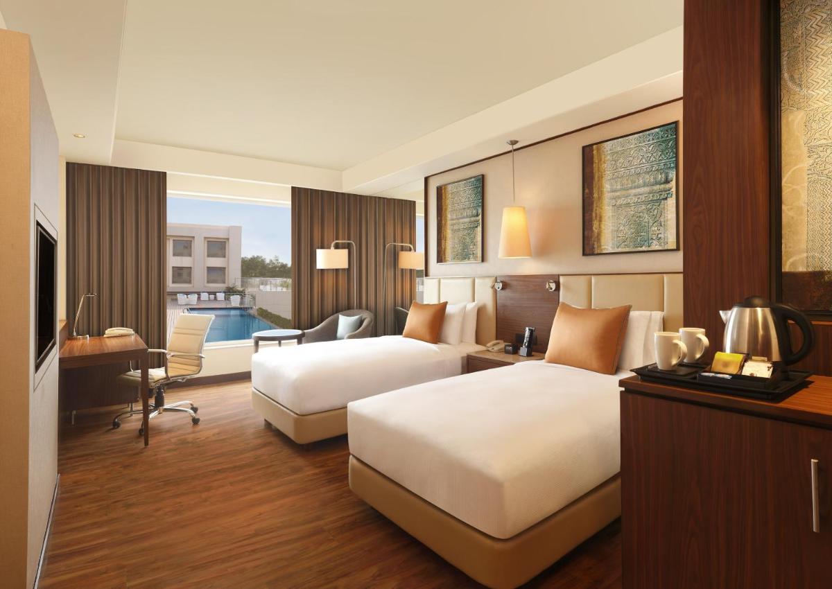 a hotel room with two beds and a desk at DoubleTree by Hilton Agra in Agra