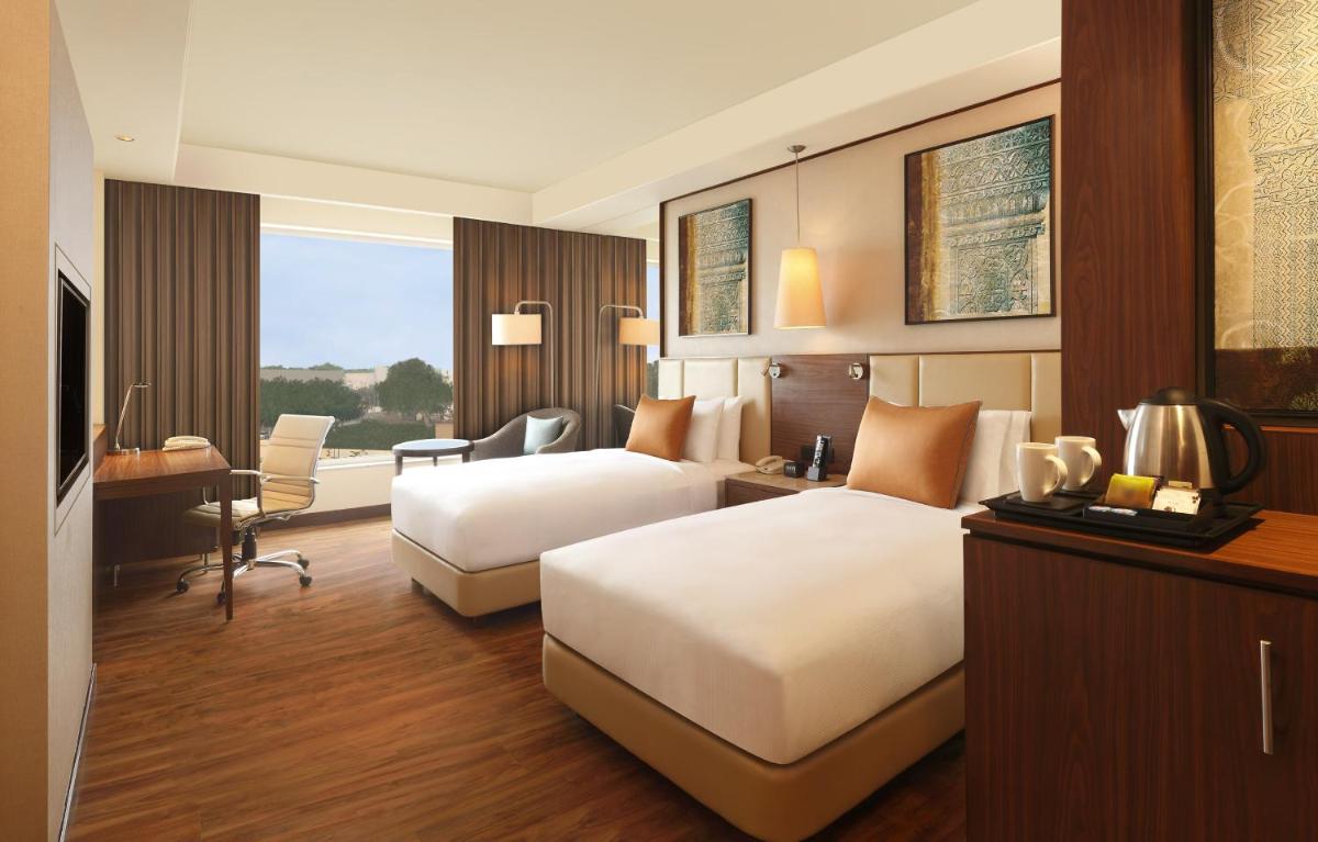 a hotel room with two beds and a desk at DoubleTree by Hilton Agra in Agra