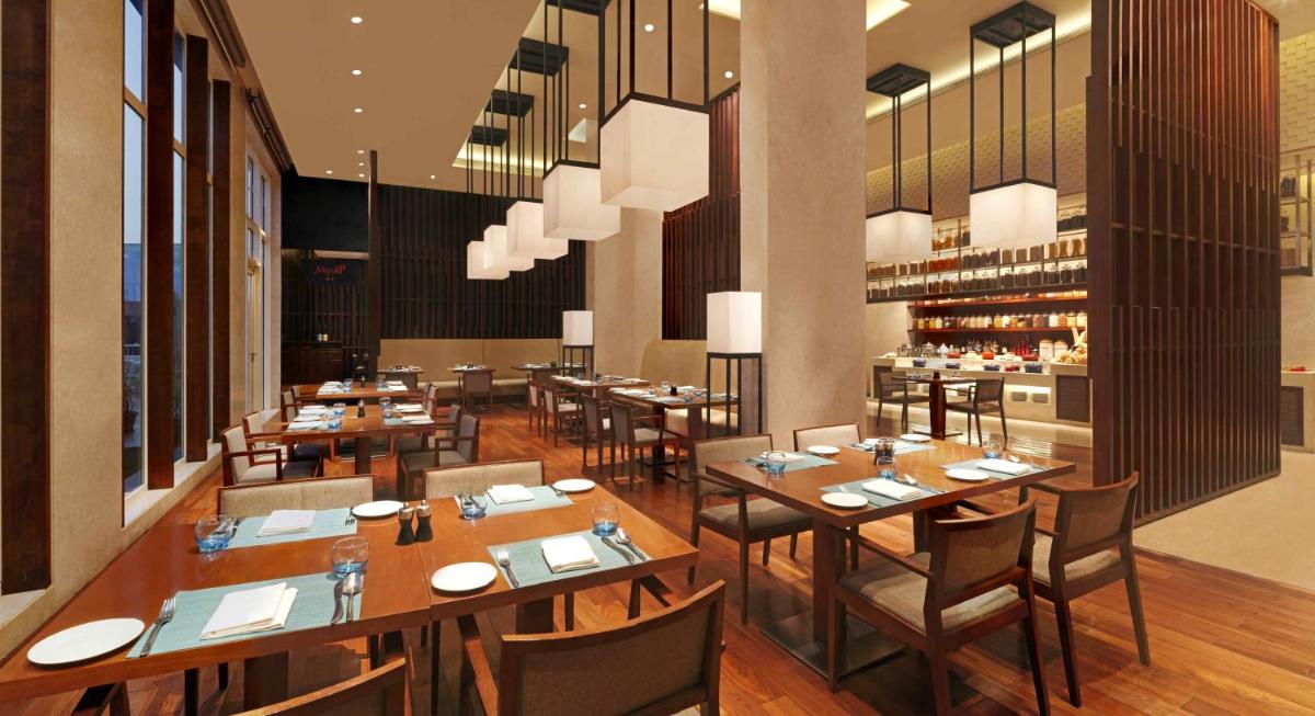 a restaurant with tables and chairs and a bar at DoubleTree by Hilton-Pune Chinchwad in Pune