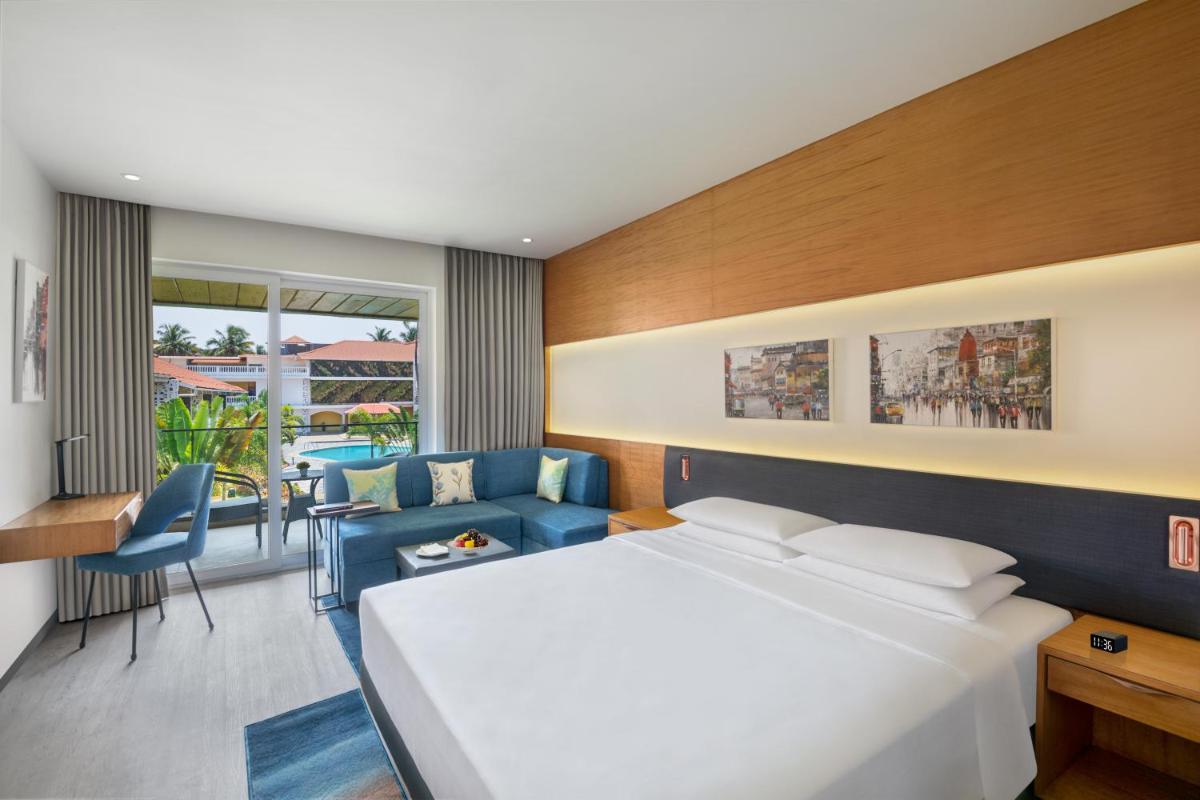 a hotel room with a bed and a living room at Hyatt Place Goa Candolim in Candolim a hotel room with a bed and a living room at Hyatt Place Goa Candolim in Candolim