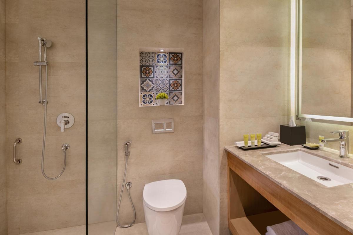 a bathroom with a shower and a toilet and a sink at Hyatt Place Goa Candolim in Candolim a bathroom with a shower and a toilet and a sink at Hyatt Place Goa Candolim in Candolim