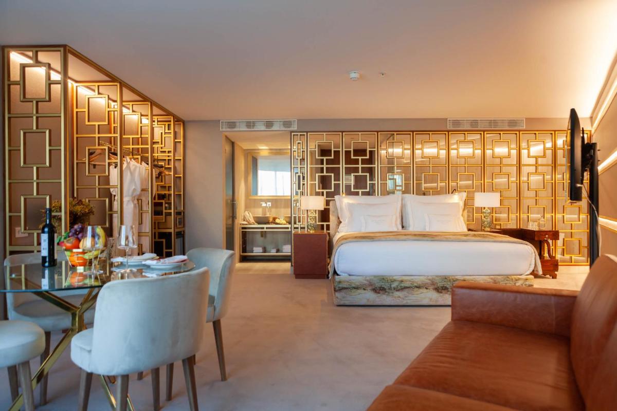 um quarto com uma cama grande, uma mesa e cadeiras em Wine & Books Lisboa Hotel em Lisboa