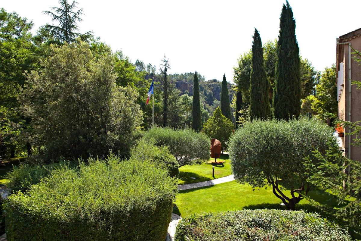 un jardin avec des buissons et des arbres et un drapeau dans l'établissement Hostellerie Les Gorges De Pennafort, à Callas