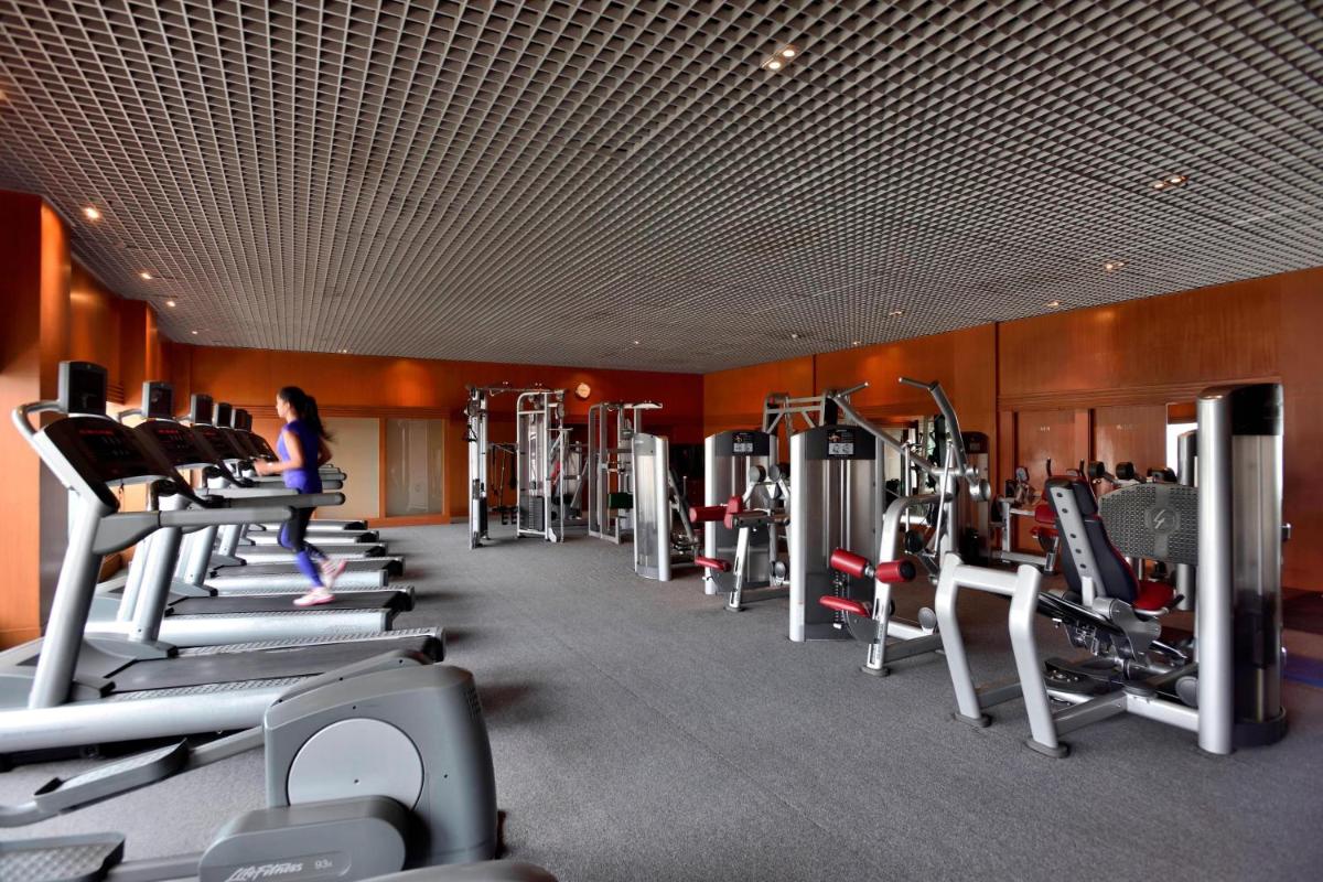a gym with a woman running on tread machines at Hyderabad Marriott Hotel & Convention Centre in Hyderabad