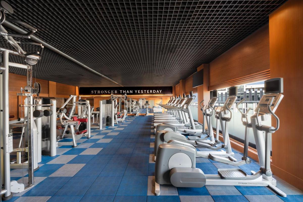 a gym with a row of tread machines at Hyderabad Marriott Hotel & Convention Centre in Hyderabad