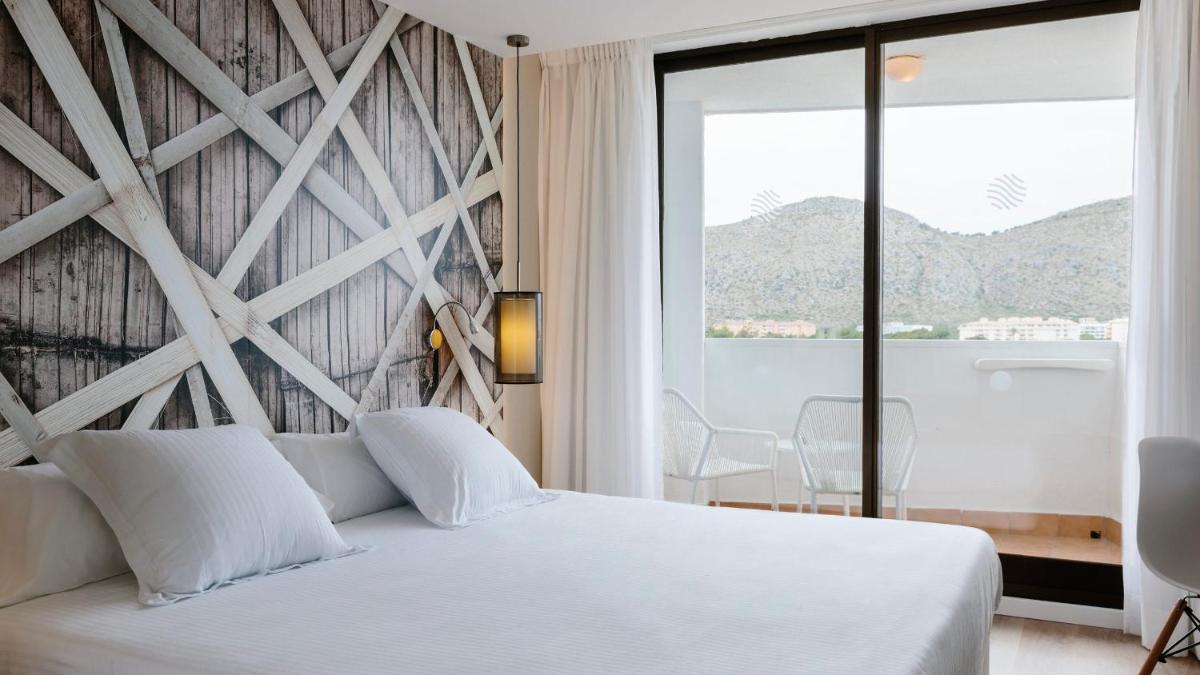 Un dormitorio con una cama blanca y una ventana grande. en Bordoy Alcudia Bay - Adults Only, en Puerto de Alcudia