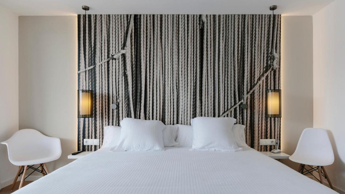 Un dormitorio con una gran cama blanca con dos sillas blancas. en Bordoy Alcudia Bay - Adults Only, en Puerto de Alcudia