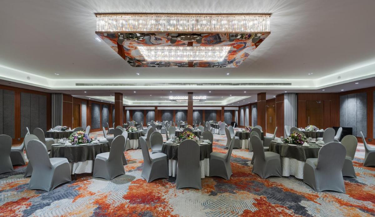 a conference room with tables and chairs and a chandelier at Southern Star,Mysore in Mysore