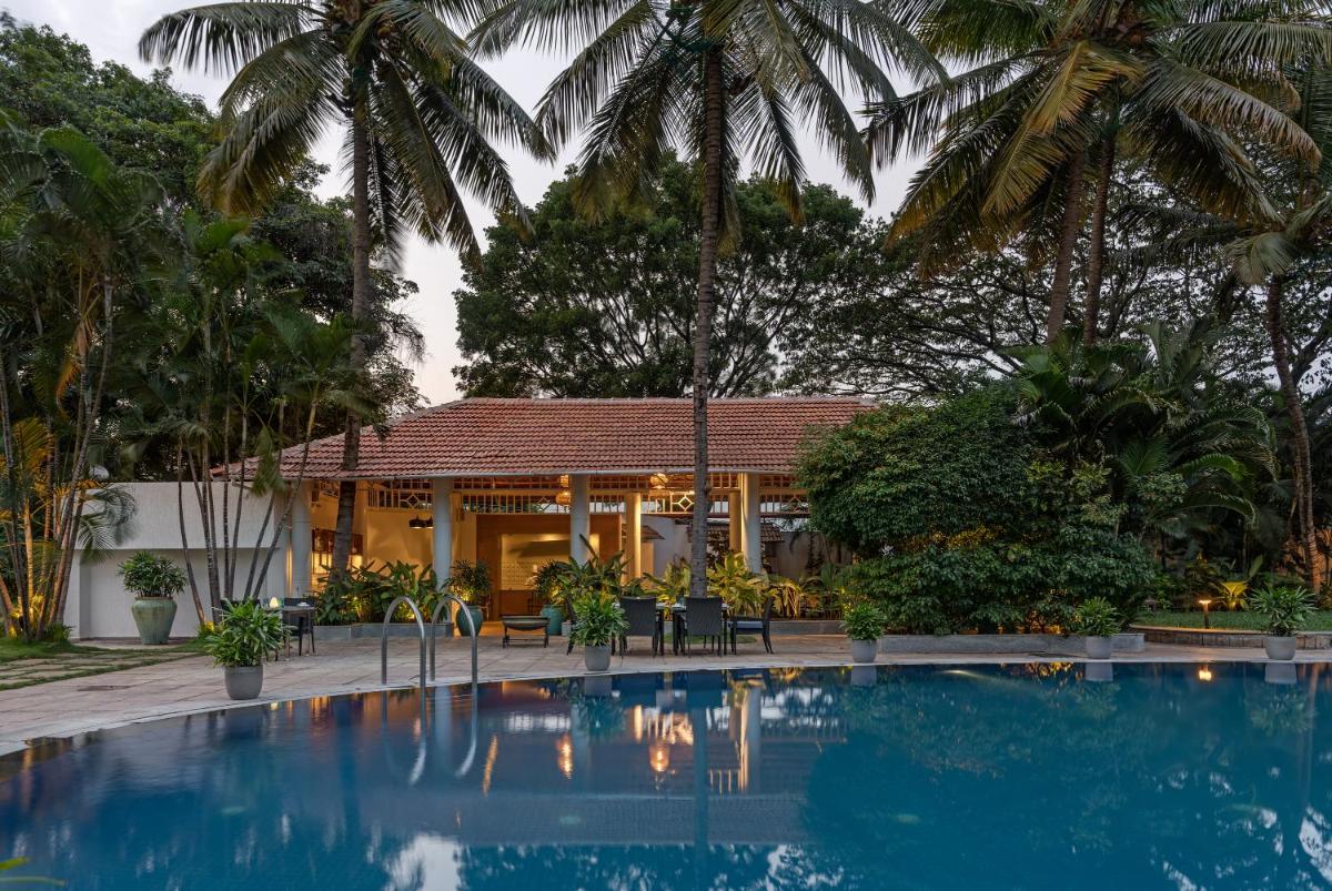 a pool in front of a house with palm trees at Southern Star,Mysore in Mysore