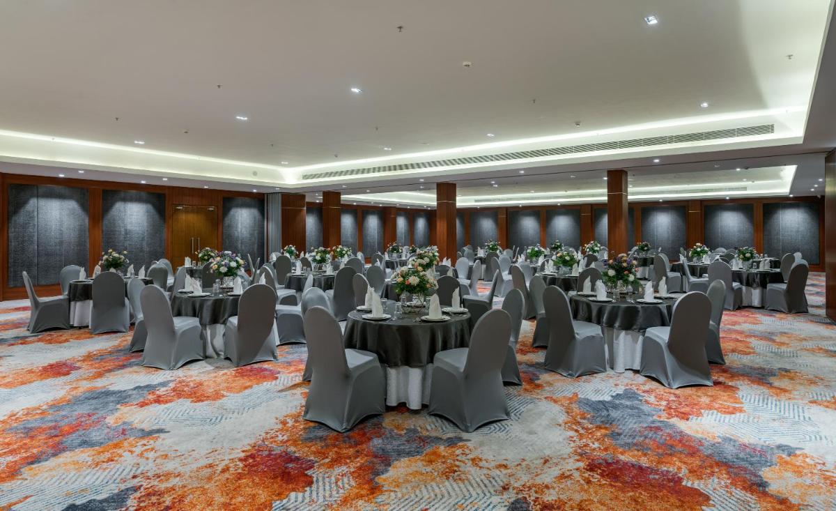 a ballroom with tables and chairs on a rug at Southern Star,Mysore in Mysore