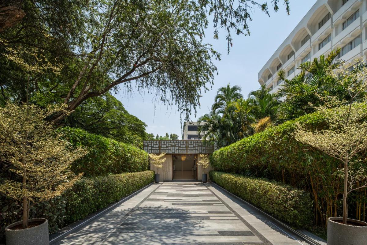 a walkway leading to a building with green hedges at Southern Star,Mysore in Mysore